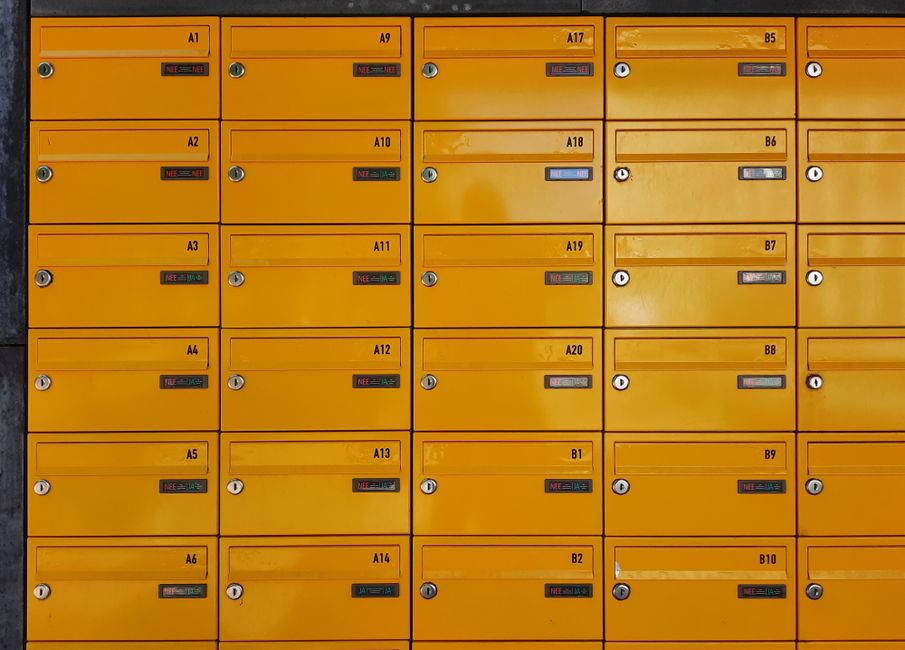 A grid of vibrant yellow apartment mailboxes with locked doors and numbered labels, offering a modern urban feel.